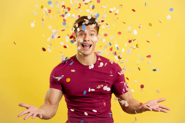 istock Cheerful man surrounded by confetti flying in the air 1474838576
