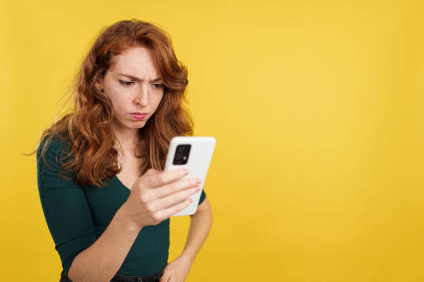 istock Worried redheaded woman using a mobile phone 1474838605