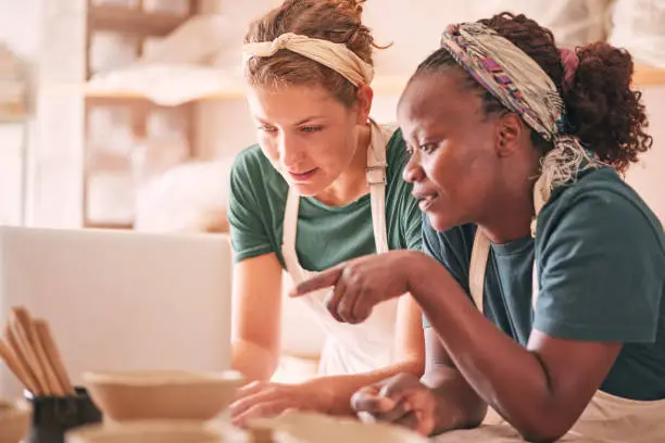 Photo of Ceramic store, laptop and pottery women pointing at retail website, online shopping service or ecommerce. Workshop, diversity studio or startup small business owner working on digital sculpture order