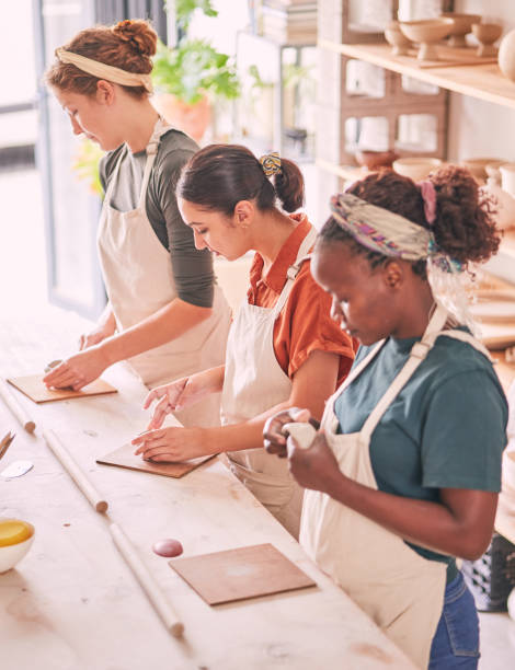 istock Pottery art and creative people row in workshop sculpting together for production process and productivity. Focus, concentration and skill of interracial team of women busy at  workspace. 1474840596