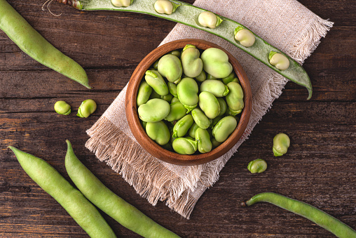 Broad bean or fava beans (Fave)  on the rustic wooden background, close-up. From garden to table, springtime vegetables and legumes for spring recipes