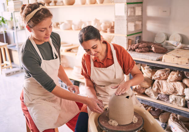 istock Pottery wheel, workshop support and women doing sculpture design mold, studio manufacturing or art product. Creative, vase molding and startup small business owner, artist or friends in ceramic store 1474842786