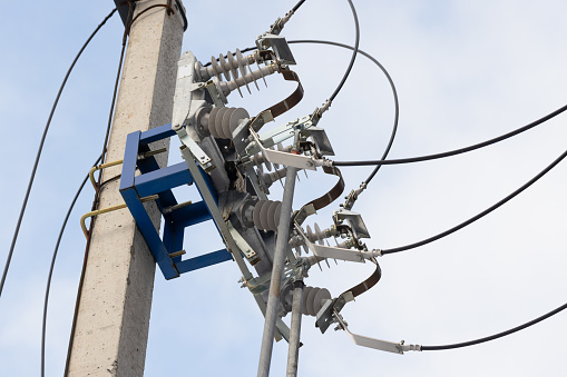 High voltage power line disconnector mounted on a concrete pole is under blue sky