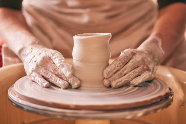 istock Hands, pottery and clay mold on table for creative art design, product or sculpture for startup workshop. Hand of crafty artist molding ceramic material in creation, shape or tool with spinning wheel 1474844123