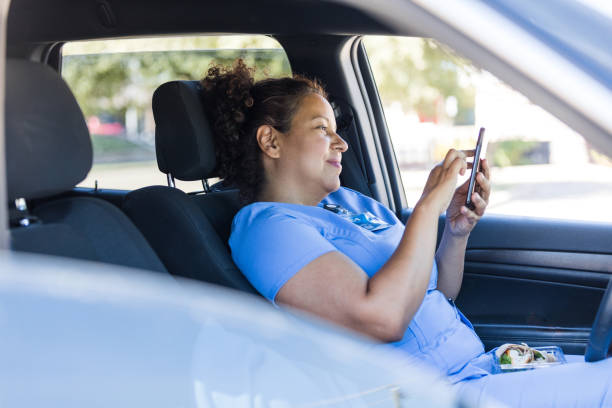 istock Taking lunch break in car, nurse surfs net on phone 1474844194