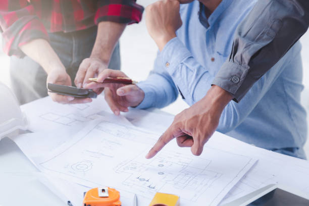 istock Construction concept of Engineer and Architect working at Construction Site with blue print, Engineer and Architect discussing construction plan with computer laptop calculator 1474845817