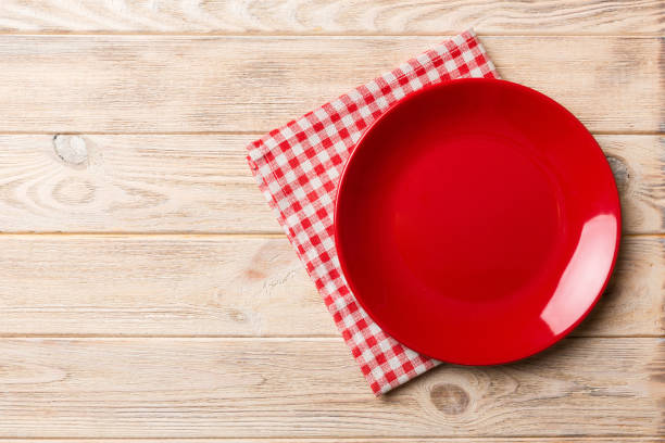 istock Top view on colored background empty round red plate on tablecloth for food. Empty dish on napkin with space for your design 1474846090
