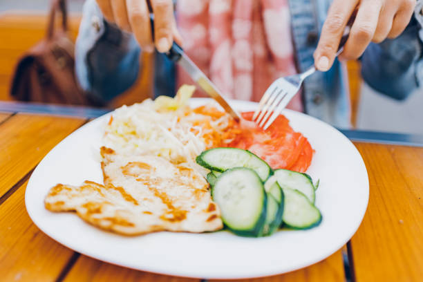 istock A woman eats chicken and salad in a restaurant 1474847352