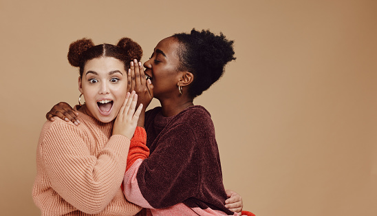Friends, gossip and women share secret on studio background and product placement mockup. Secrets, rumours and surprise whisper in ear, black woman with happy woman discuss discount sale announcement