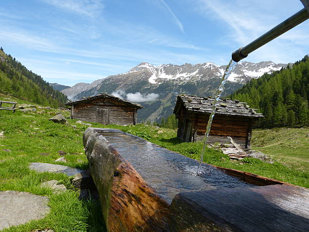 hütten mit hölzernen gut - bergwiese stock-fotos und bilder