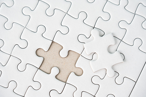 White jigsaw puzzle background for business concept of strategy solution. Teamwork and partnership concept using jigsaw pieces. Unfinished jigsaw as empty space as problem and development idea.