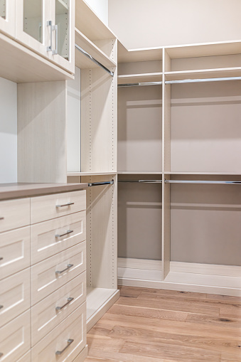 Walk-in closet shelves, chest of drawers in modern minimalist white style in staging model house apartment bedroom with wooden floors