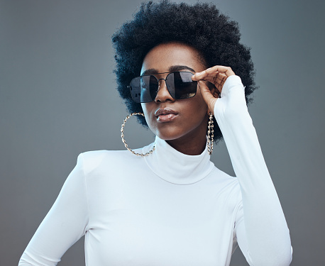 Sunglasses, fashion and young black woman with gen z style and designer with trendy brand against studio background. Afro hair, edgy and girl, marketing with fashion model and stylish beauty