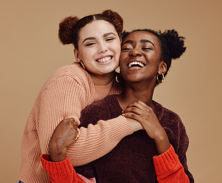 Lesbian, couple hug with young women and happy with fashion and marketing, love and fun together against studio background. Lgbtq community, gen z and freedom with style and lgbt people with pride