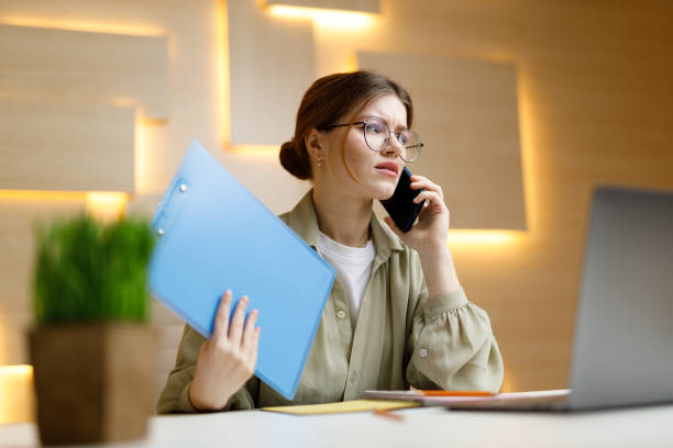 istock Anxious young businesswoman in the workplace talking on the phone, problems. 1474852629