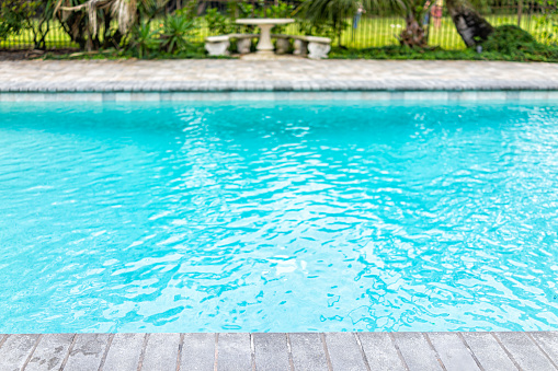 Generic blue saltwater pool in tropical setting with closeup of water and nobody in garden as copy space background