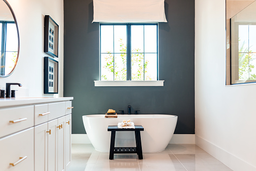 Bañera en baño puesta en escena modelo casa casa u hotel con modernos gabinetes blancos de lujo interior, ventana con luz y espejos photo