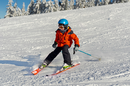 Boy enjoying ski on slope in the mountains, sunny day, wintertime