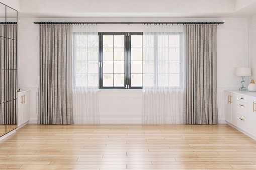 Front view of a cozy retro-chic elegant unfurnished interior with low white hardwood cabinets on both sides, a large and high mirror cabinet in front of a white wood paneled wall with moldings and decoration (lamps, vases, books). Large retro black windows covered with white and beige textile long curtains in the middle and on the hardwood floor.  A slight vintage effect was added. 3D rendered image.