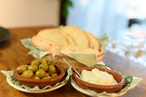 Olives, mayonnaise and bread served on a table of a restaurant