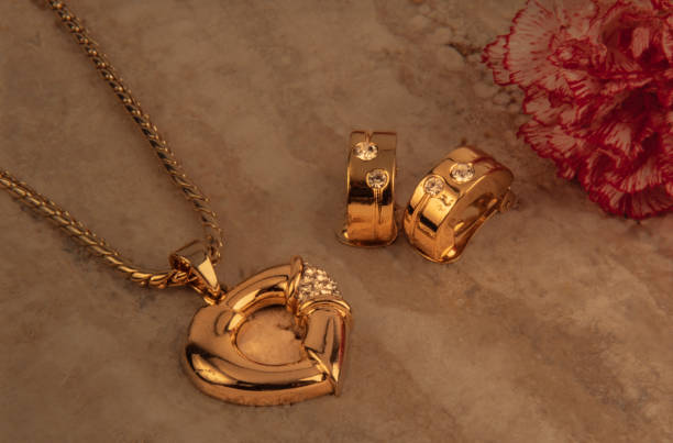 golden pendant on a stone background with a red carnation