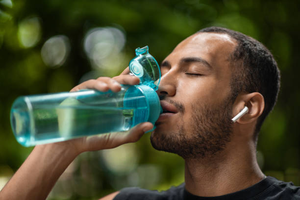 istock Sporty african american man drinking water, training at park 1474865049