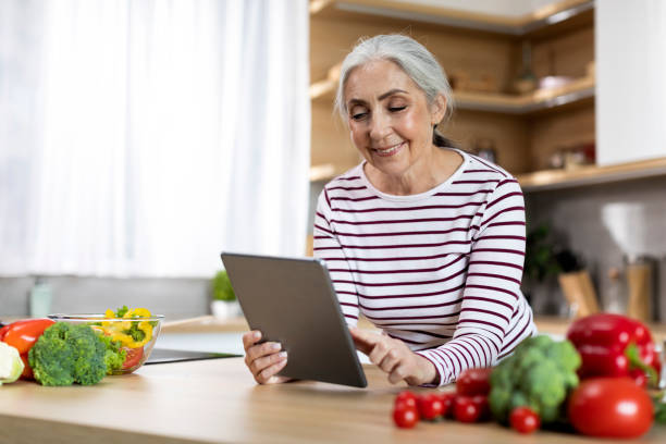 istock Portrait Of Happy Senior Woman Using Digital Tablet While Cooking In Kitchen 1474866910