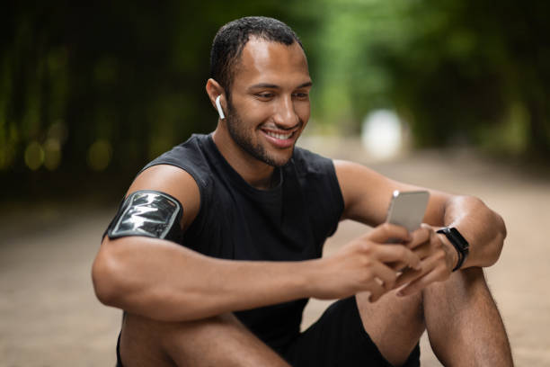 istock Happy black sportsman having break, using modern smartphone 1474866944