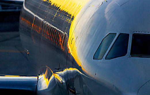 Abstract, beautiful and symbolic sunset sky colors reflected in passenger jet airplane fuselage.