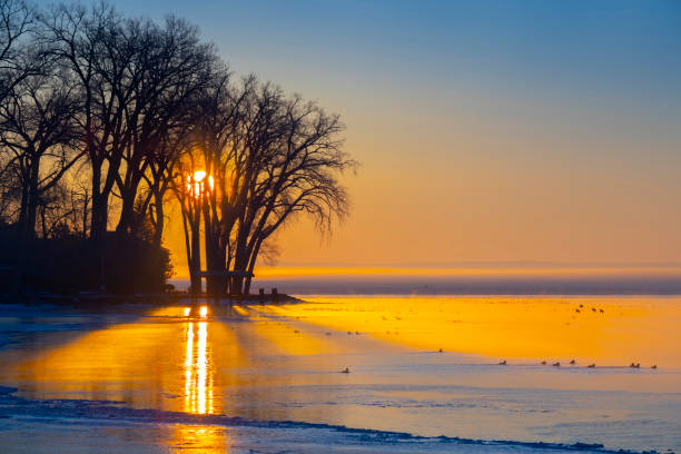 Stunning sunrise over partly frozen lake, steaming waters with sea birds.