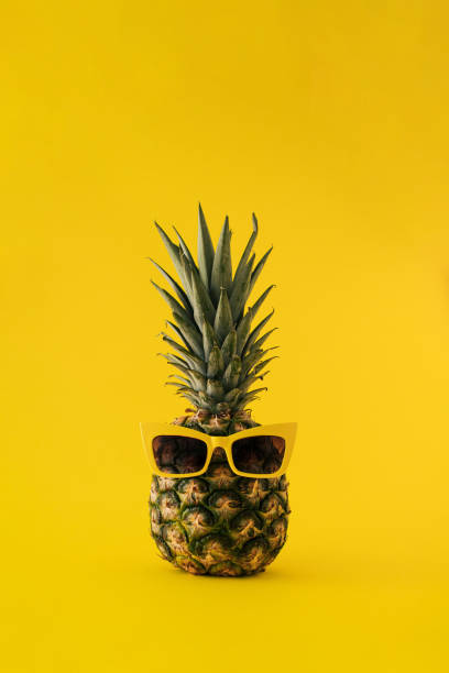 istock Fresh pineapple with sunglasses on yellow background. Minimal summer furit concept. 1474872520