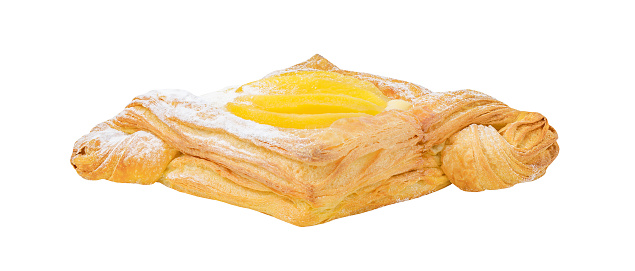 Sweet puff pastry with peaches, cream and powdered sugar, side view, isolated on white background with clipping path