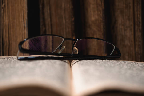 istock Open blurred page with hebrew religious text, glasses and old shabby leather-bound Jewish books Chumash on the background. Concept of studying and reading Torah. Selective focus on glasses. Closeup. 1474876151