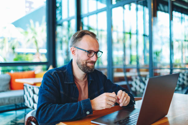 istock Adult man working from cafe using laptop for video call, positive and smiling 1474879079