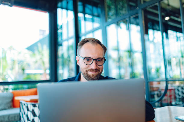 istock Adult man working from cafe using laptop for video call, positive and smiling 1474879086