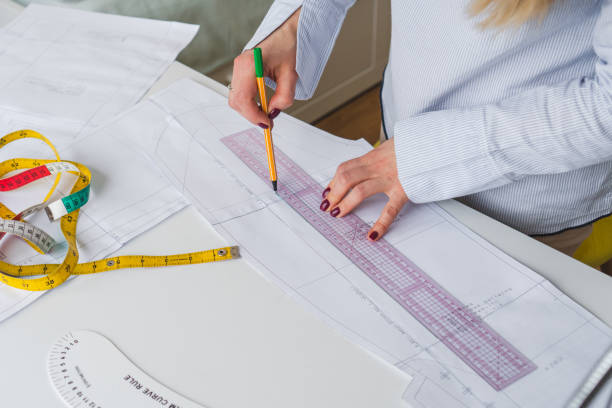 istock Female designer drawing paper patterns. Exclusive clothes making concept. Workplace of seamstress 1474882265