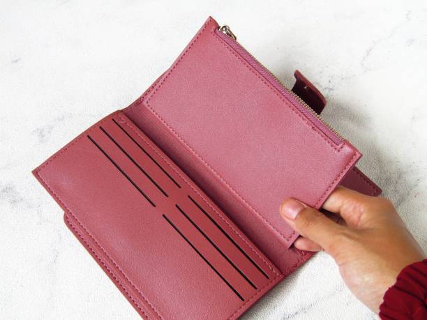 istock Women's wallet in dark pink color, on a white background. Hands in frames. 1474885365