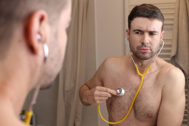 Cute man listening to his own heartbeat stock photo