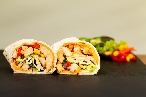 Closeup of tortilla wrap in closed wrap served on a black tray