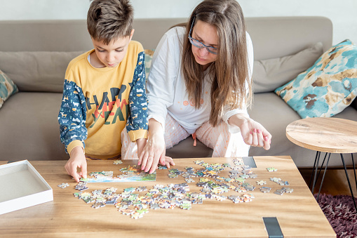 Mother and son working on a puzzle on a weekend morning, they are enjoying time together