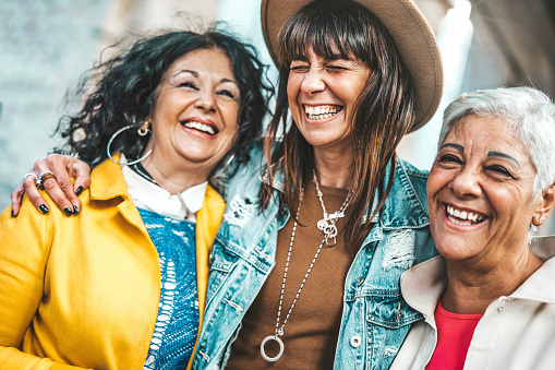Tres mujeres mayores divirtiéndose riendo a carcajadas afuera - Amigas felices hablando juntas caminando por la calle de la ciudad - Concepto de estilo de vida con mujeres maduras colgando al aire libre en vacaciones de verano photo