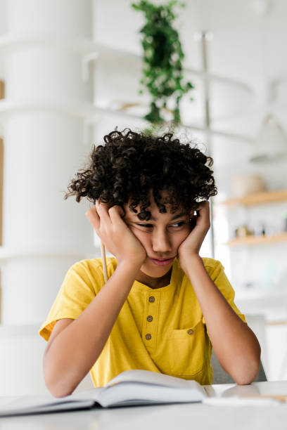 istock Sad tired frustrated boy sitting at the table with many books and doing homework. Learning difficulties, education concept 1474892260