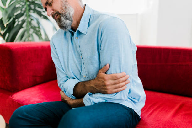 istock Senior man feeling unwell, suffering from backache, massaging aching muscles while sitting on sofa in the living room at home. Elderly and health issues concept 1474892509