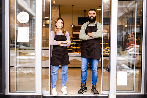 istock Proud owners standing with arms crossed in front of their store 1474893367