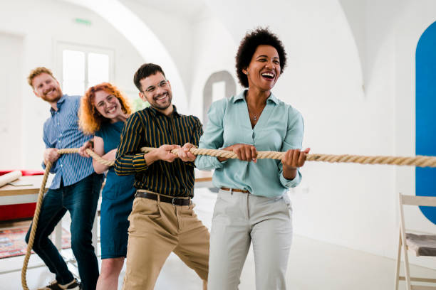 spielerische unternehmer, die im büro tauziehen spielen - rope pulling stock-fotos und bilder