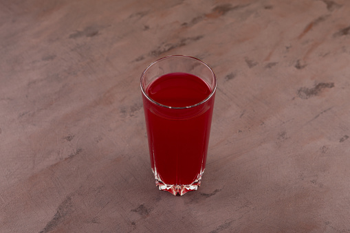 Glass of Salgam or fermented beet juice on brown background, selective focus. Popular Turkish drink. Traditional beverage made with water, purple carrot or turnip (juice).