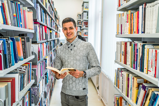 Portrait of a smiling young male student in the college library