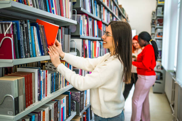 istock Young female student picking a book from library bookshelf 1474897042