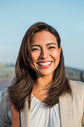 Portrait of a beautiful latin woman smiling outdoors with sunset light. Vertical image