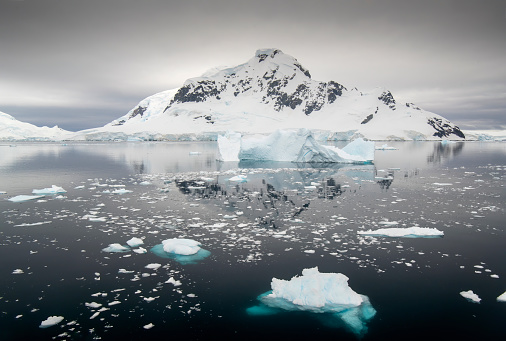 Massive Iceberg floating in the Southern Ocean in Antarctica with snow covered mountains in the background